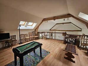 A loft-style room with a pool table, wooden chairs, a billiards rack, and a billiard cue rack. - Le Pin de la Tour - SOSSAIS (SOSSAIS)