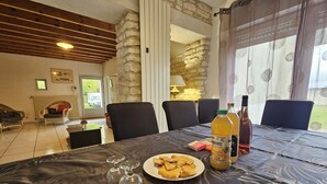 Een eetgedeelte met een tafel gedekt voor twee personen, een fles sap en een bord eten.