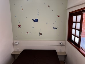 Una habitación con una cama, un ventanal y una pared decorada con calcomanías de animales marinos.