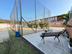 Un espacio al aire libre cercado con bancos, un contenedor de basura y plantas en macetas.