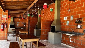 Een terras met bakstenen muren, houten tafels en banken, een bakoven en hangende decoraties.