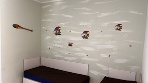 Een kamer met twee eenpersoonsbedden, een houten roeiblad aan de muur en decoratieve muurstickers van vissen en zeesterren.