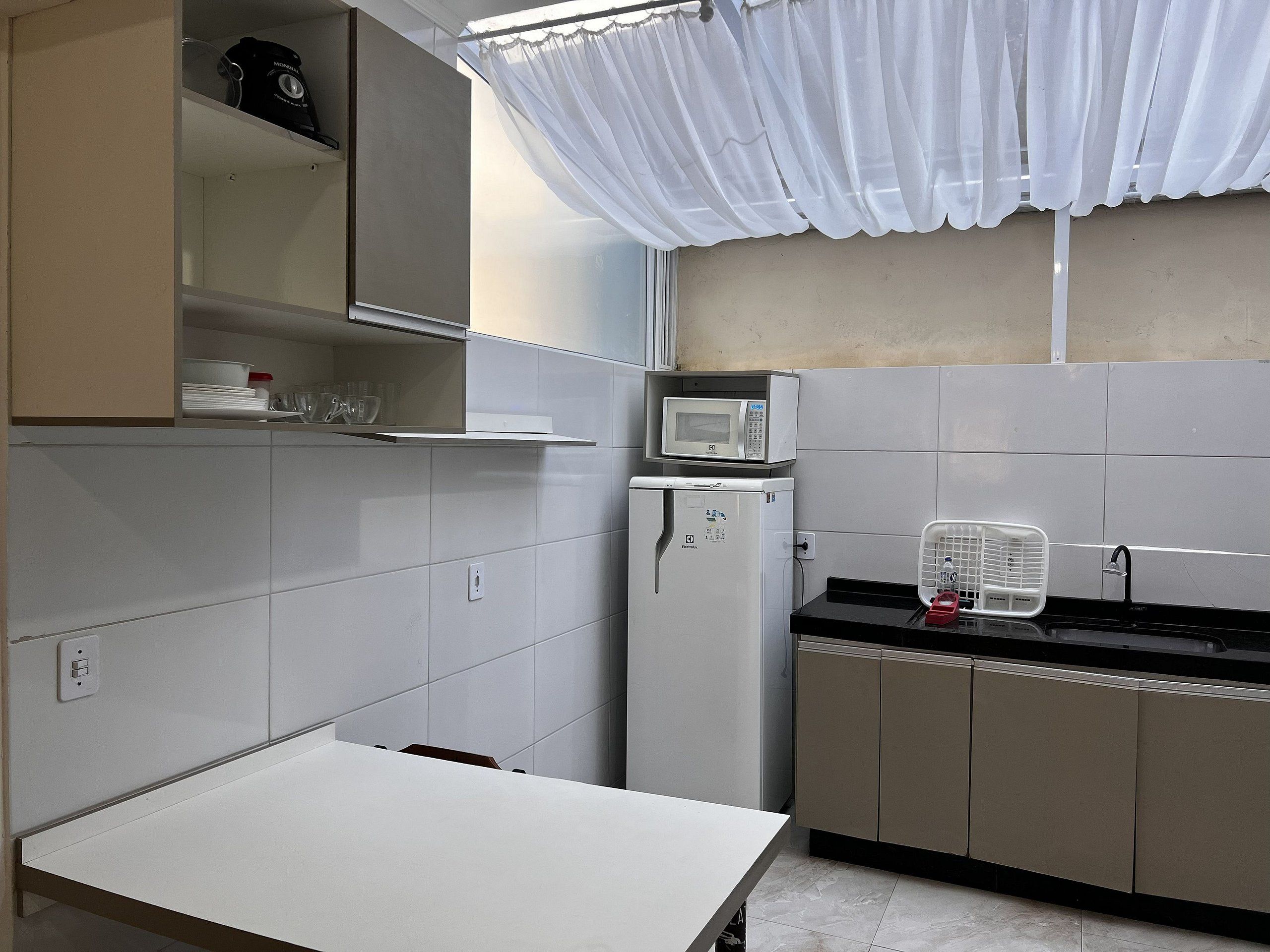 A kitchen with white cabinets, a microwave, a refrigerator, and a sink.