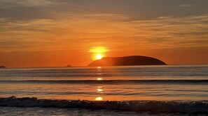 A sunset over the ocean with a silhouette of an island. - Reserve MV2 (Ubatuba)