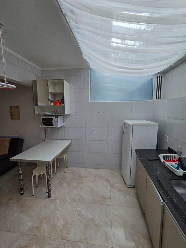 Una cocina compacta con una mesa de comedor, microondas, refrigerador y ventana con vistas.