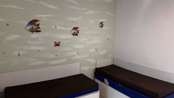 Una habitación con dos camas, una pared decorada con peces y estrellas, y una lámpara en el techo.