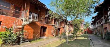 A brick building with multiple balconies and a central tree.