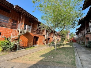 A brick building with multiple balconies and a central tree. - Reserve MV2 (Ubatuba)