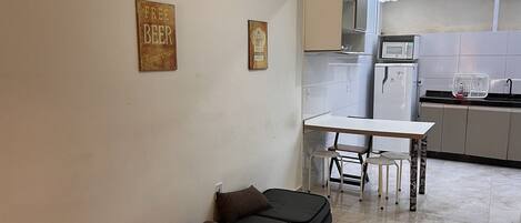 A compact kitchen with a dining area, a microwave, and a refrigerator.