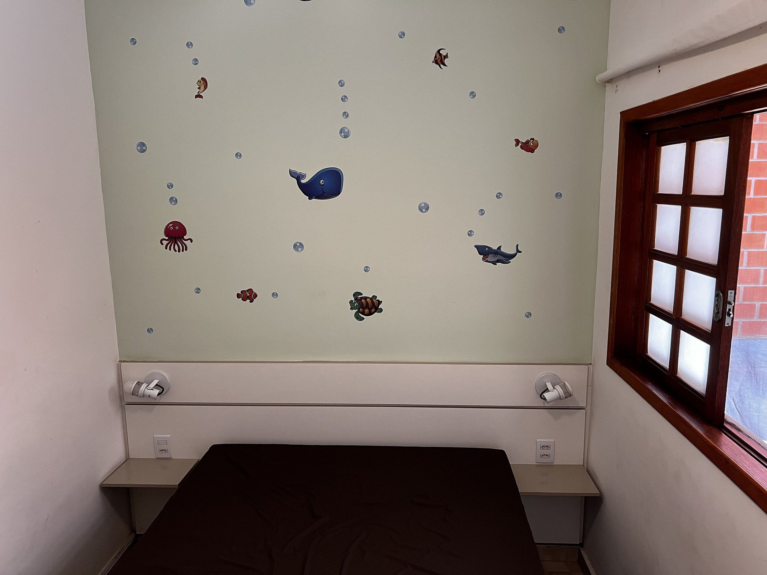 Una habitación con una cama, un ventanal y una pared decorada con calcomanías de animales marinos.