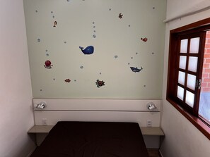 Una habitación con una cama, un ventanal y una pared decorada con calcomanías de animales marinos.
