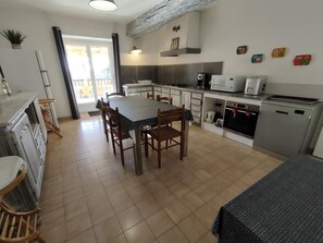 Een moderne keuken met een eettafel, stoelen en diverse apparaten.
