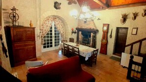 Ein Essbereich mit Tisch, Stühlen, Kamin, einer Uhr und einer Treppe.