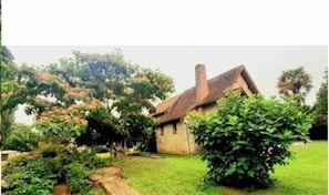 A small stone building with a sloped roof, surrounded by lush greenery and trees. - XIth century Priory - BONNES (BONNES)