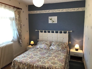 A bedroom with a bed, two bedside tables with lamps, a radiator, and a window with curtains. - La Forge de Louis - SAINT-MACOUX VAL DE COMPORTE (SAINT-MACOUX VAL DE COMPORTE)