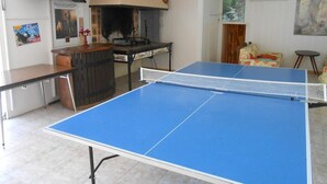 Ett bordtennisbord i ett rum med ett kaklat golv, ett träbord och en affisch på väggen.