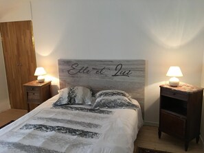 A bedroom with a bed, two bedside tables with lamps, a wooden wardrobe, and a headboard with a name plaque. - L'Ammonite - CHAUNAY (CHAUNAY)