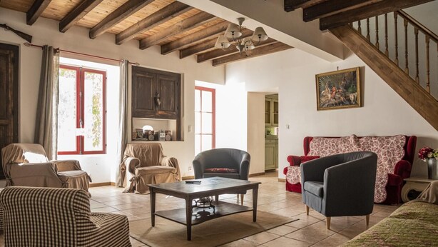 A spacious living room with a high ceiling, wooden beams, a fireplace, and a staircase. - La Maison d'Irène - ANCHE (ANCHE)