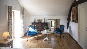 A room with two blue armchairs, a round table with a potted plant, a dark wooden dresser, and a white door. - La Maison d'Irène - ANCHE (ANCHE)