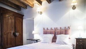 A bedroom with a wooden wardrobe, a bed with white bedding, two bedside lamps, and a nightstand. - La Maison d'Irène - ANCHE (ANCHE)