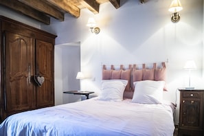 Une chambre à coucher avec une armoire en bois, un lit avec une literie blanche, deux lampes de chevet et une table de chevet.