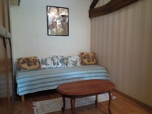 Una habitación con una cama, un banco de madera, un espejo en la pared y una ventana con cortinas.