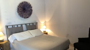 Een slaapkamer met een bed, twee bedlampjes, een ronde wanddecoratie, een stoel en een wit tapijt.