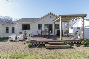 Ein Haus mit überdachter Terrasse, Sitzgelegenheiten im Freien und einem kleinen Garten.