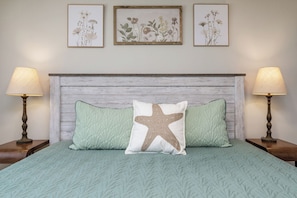 A bed with a white headboard, two bedside lamps, and two pillows, one with a starfish design.