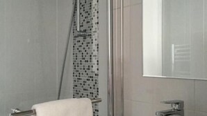 Een moderne badkamer met een douche, een wastafel en een spiegel.