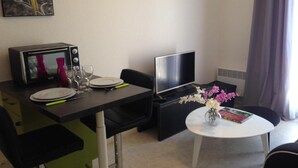 Een knus hotelkamer met een zithoek, een flatscreen televisie, een tafeltje met een bloevas en een schilderij aan de muur.