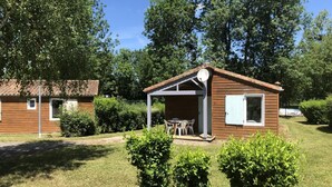 Una pequeña cabaña de madera con un porche, rodeada de follaje.