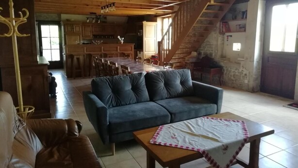 Zona d'estar acollidora amb un sofà, una taula i una escala que condueix a una cuina.