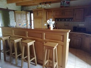 Eine Küche mit Holzausstattung, einer zentralen Kochinsel mit Sitzgelegenheiten und einer hängenden Leuchte.