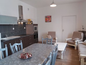 Une cuisine compacte avec un coin repas, un canapé et une table sur laquelle se trouve un saladier rempli de fruits.
