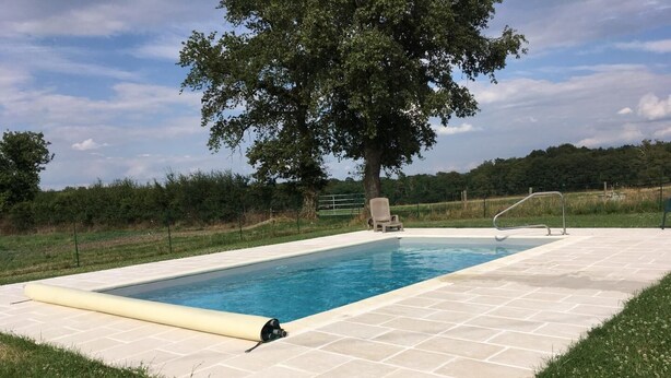 A rectangular swimming pool with a tiled deck, a tree in the background, and a grassy area. - Le Petit Gîte - LATHUS-SAINT-REMY (LATHUS-SAINT-REMY)