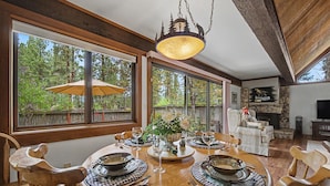 Un espace repas avec une table ronde dressée pour six personnes, entourée de chaises en bois.