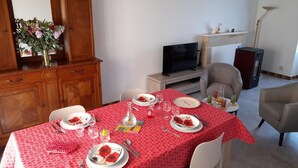 Un coin repas avec une nappe rouge, des meubles en bois, un téléviseur et une cheminée.