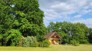 A small wooden cabin with a porch, surrounded by lush greenery and trees. - Asia - BUSSIERE (LA) (BUSSIERE (LA))
