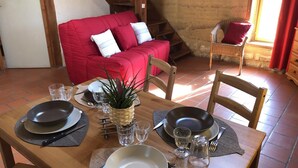 A dining area with a wooden table set for two, a red sofa, and a wicker chair. - Asia - BUSSIERE (LA) (BUSSIERE (LA))