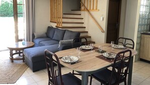 A dining area with a wooden table set for four, a sofa, and a staircase. - Le Relais de la Motte (THURE)
