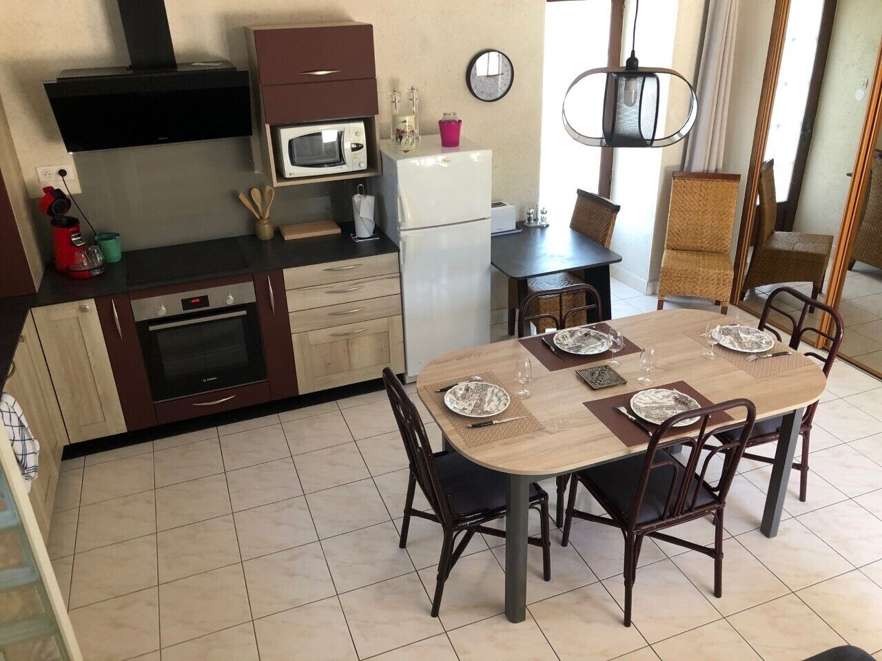 A kitchen with a dining table set for four, a microwave, a refrigerator, and a stove.