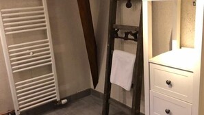 A bathroom with a white radiator, a wooden ladder, and a white vanity with drawers. - Le Relais de la Motte (THURE)
