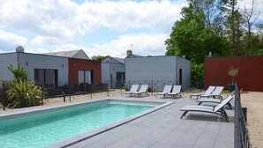 Una piscina amb gandules i un edifici amb façana vermella.