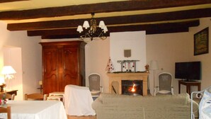 Un salon avec une cheminée, un téléviseur et un coin repas comprenant une table et des chaises.