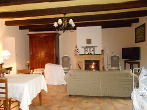 A living room with a fireplace, a television, and a dining area with a table and chairs. - Gîte des Quatre Vents - SAINT-MACOUX (SAINT-MACOUX)