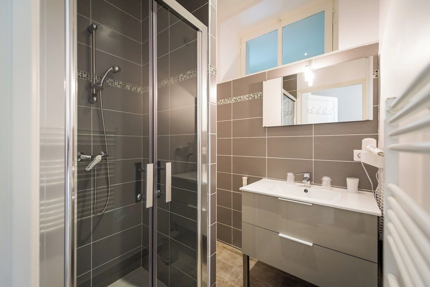 A modern bathroom with a glass-enclosed shower, a white sink, and a mirror above it.