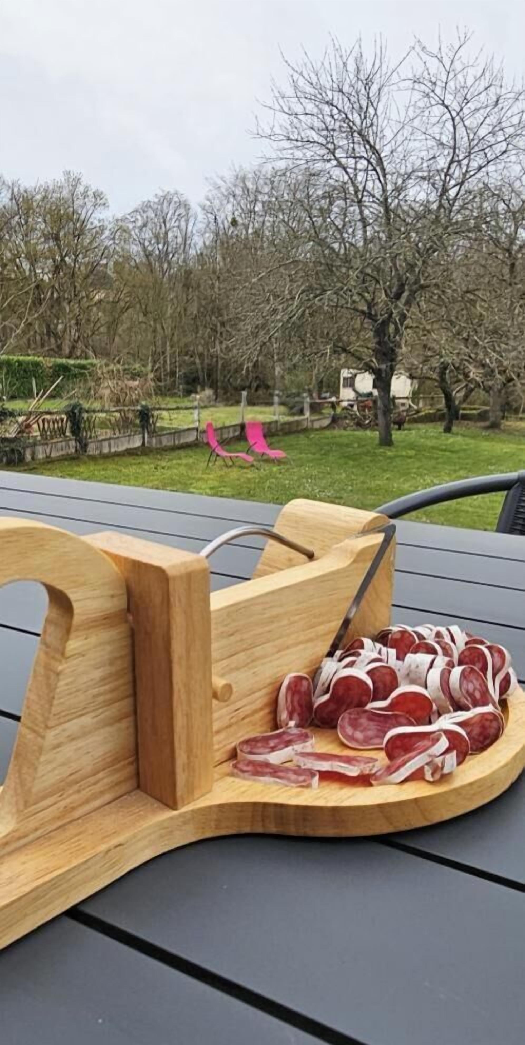 Ein Holz-Fleischschneidegerät mit geschnittenem Fleisch auf einem Tisch im Freien.