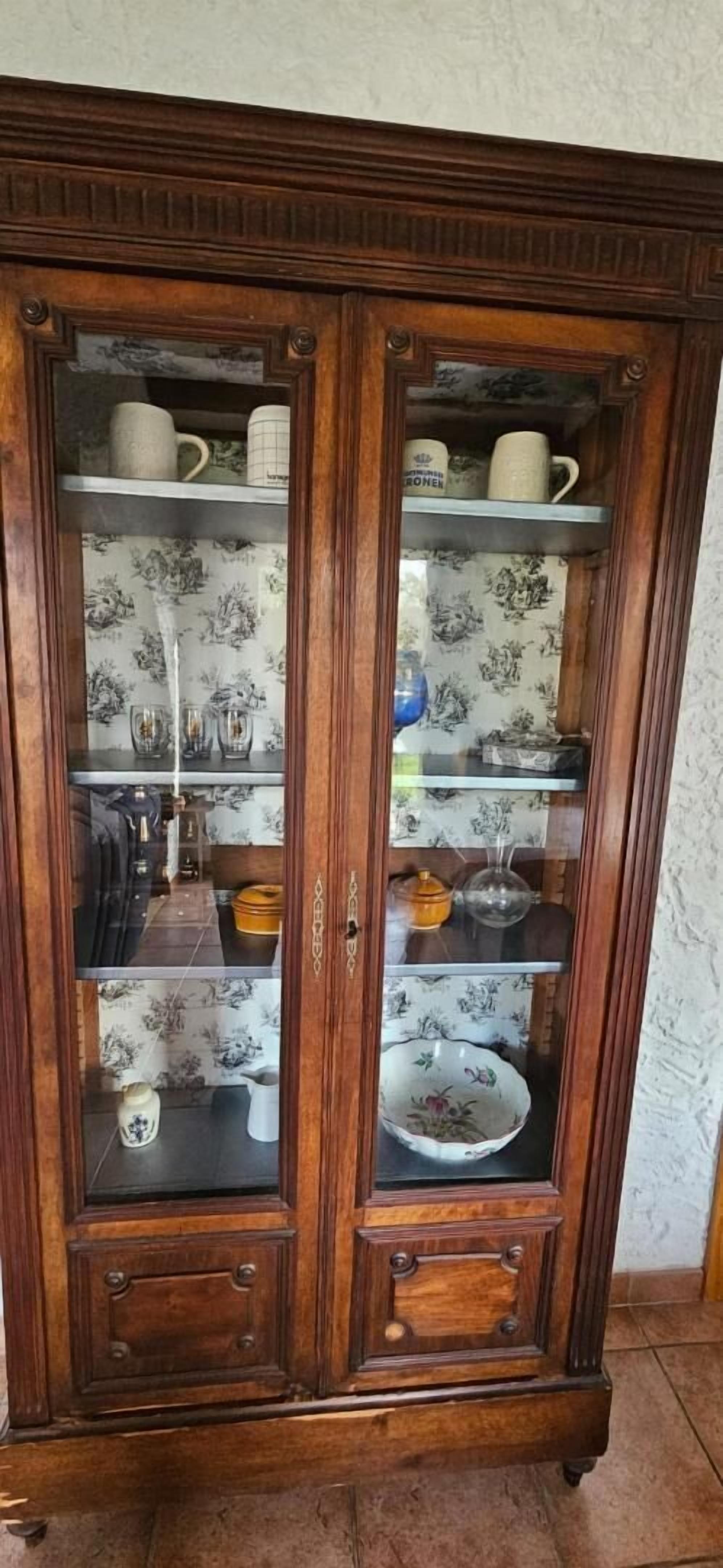 Een houten kast met glazen deuren, planken en lades.