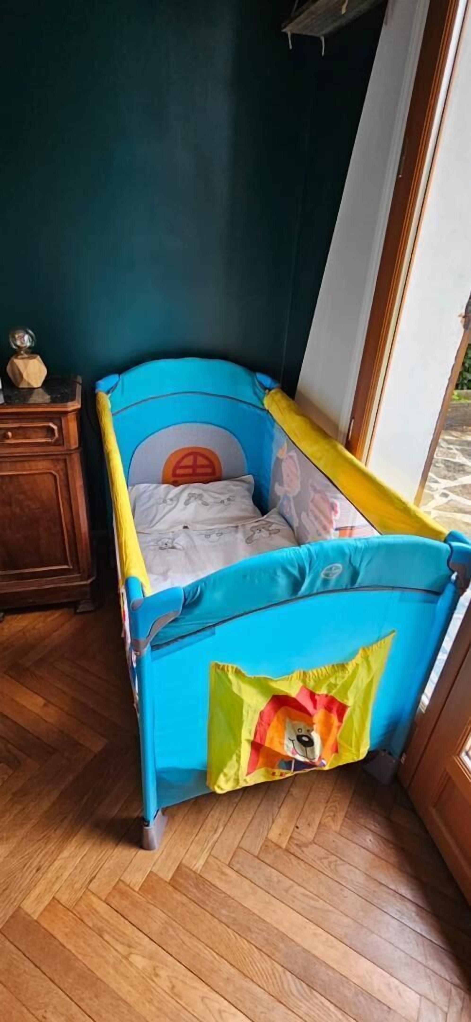 Ein Eckzimmer mit einem Spielbett in Blau, Holzboden und einem Fenster.